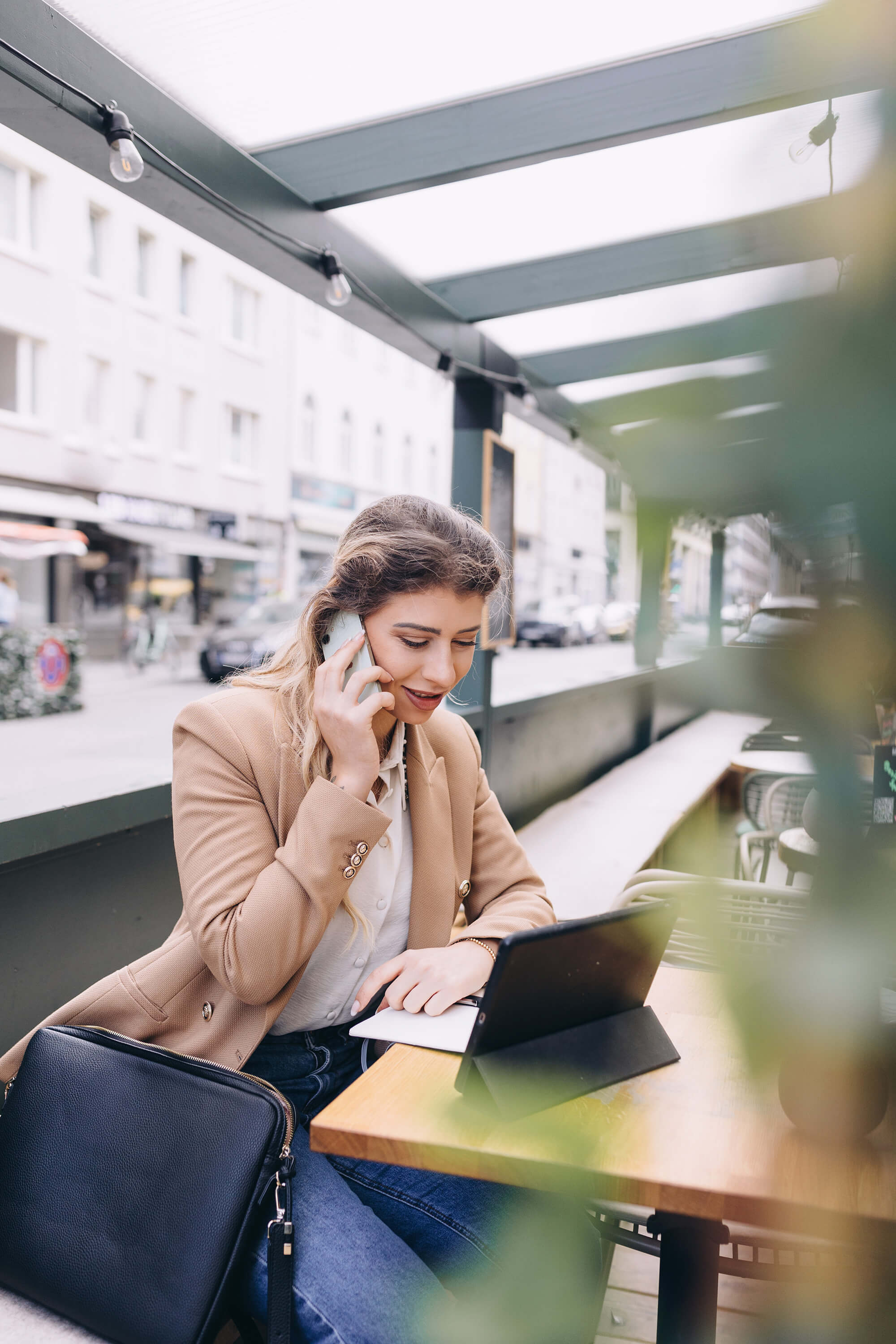 Woman working in a public space on a laptop while talking on the phone.